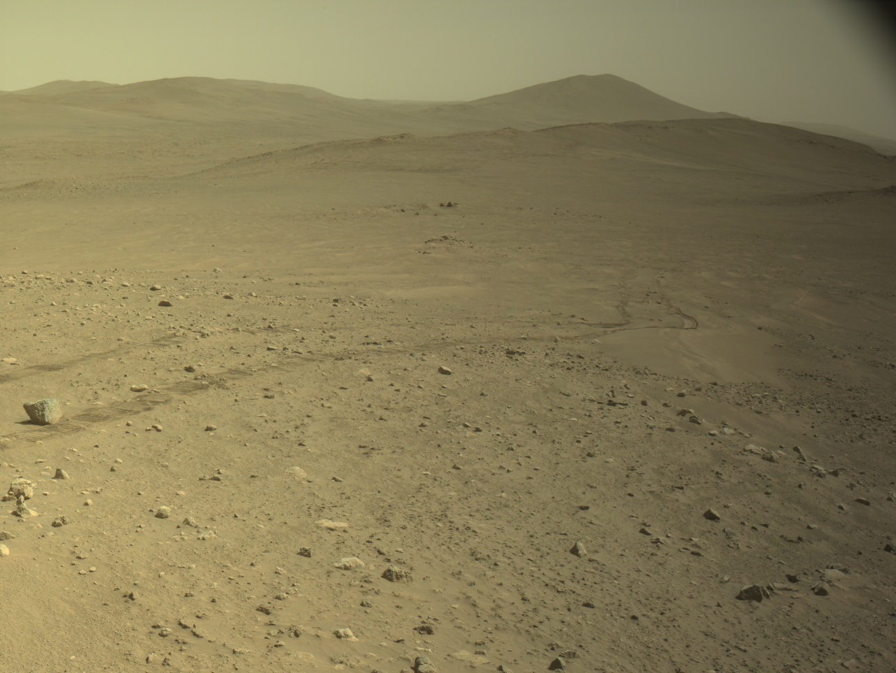 火星の地表に残るパーサビアランスの車輪の跡と遠くの丘