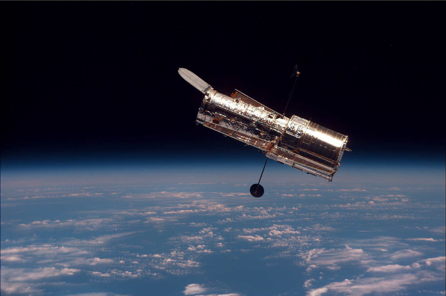 地球の縁を背景に軌道を周回するハッブル宇宙望遠鏡
